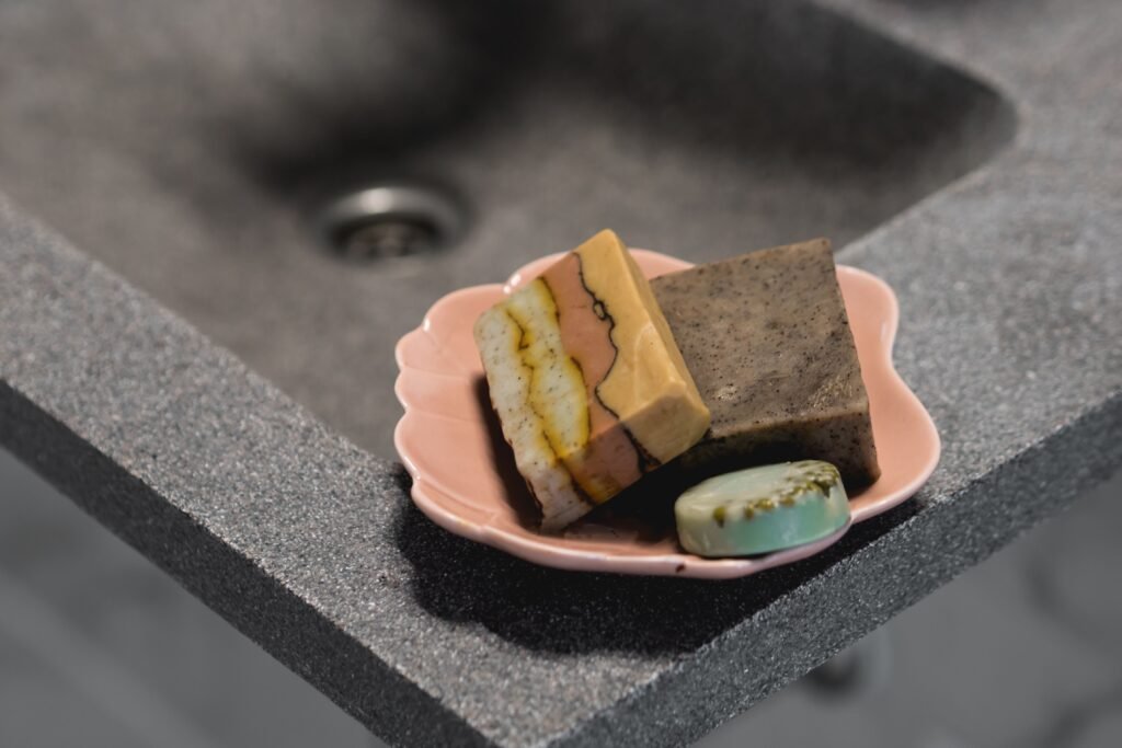 Close-up still life of handcrafted soaps on a pink tray, highlighting self-care and skincare essentials.